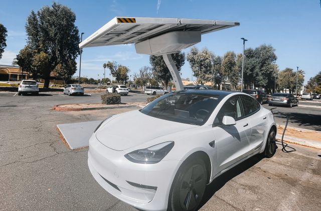 Voiture électrique rechargée sous des panneaux solaires en autoconsommation