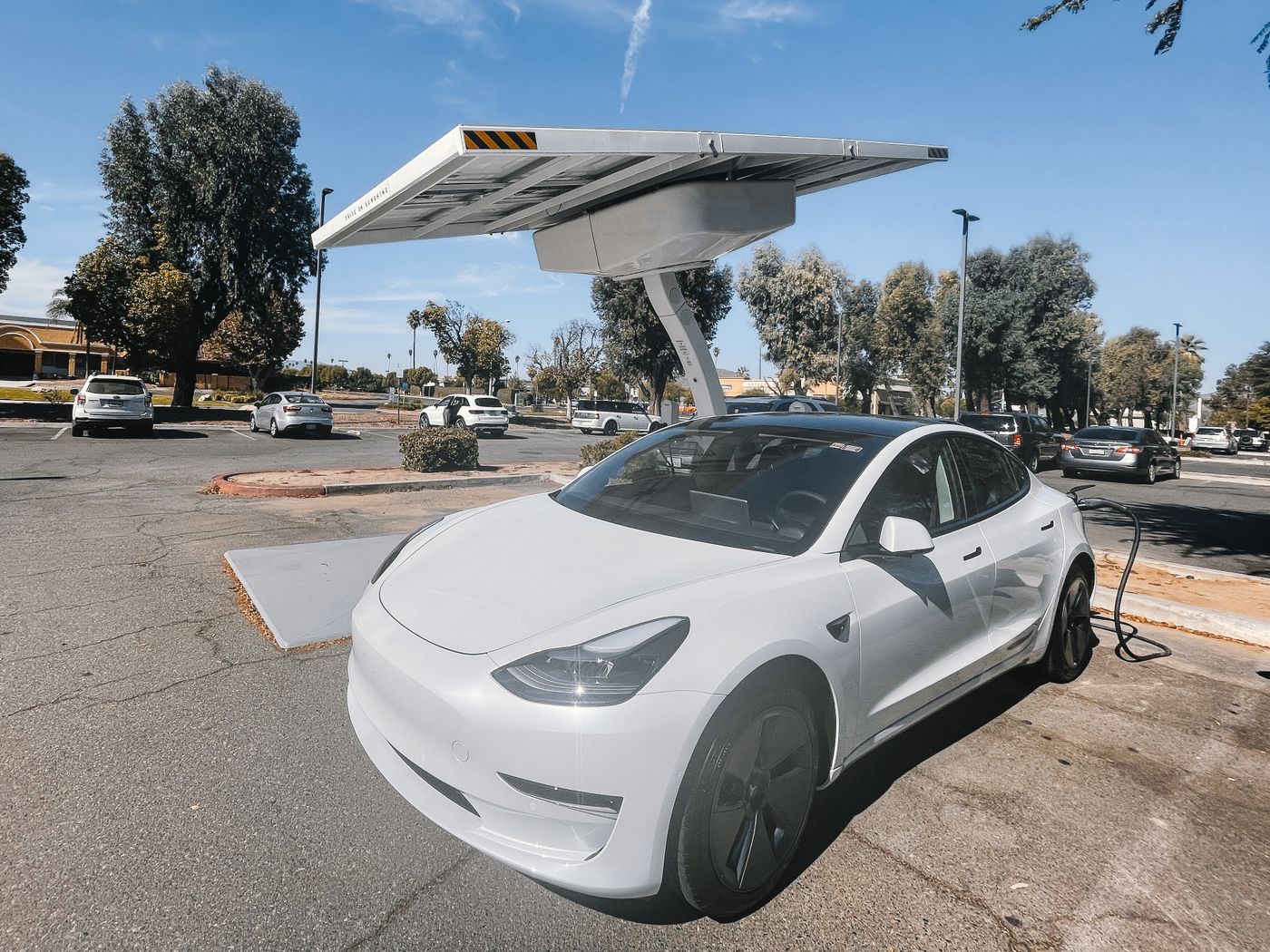 Voiture électrique rechargée sous des panneaux solaires en autoconsommation