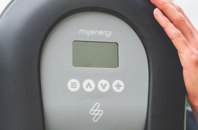 Main vérifiant l'écran d'une borne de recharge lors de son entretien