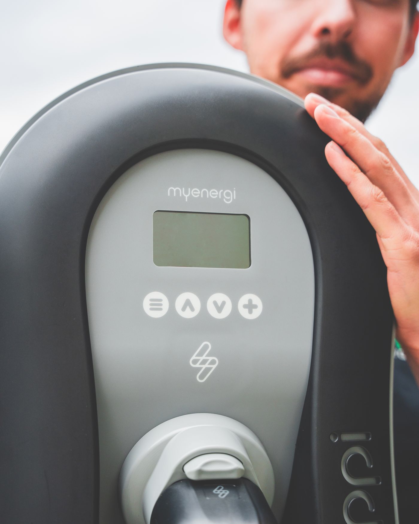 Main vérifiant l'écran d'une borne de recharge lors de son entretien