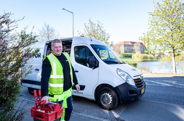 Technicien souriant avec sa camionnette et sa caisse à outils, installateur près de chez soi