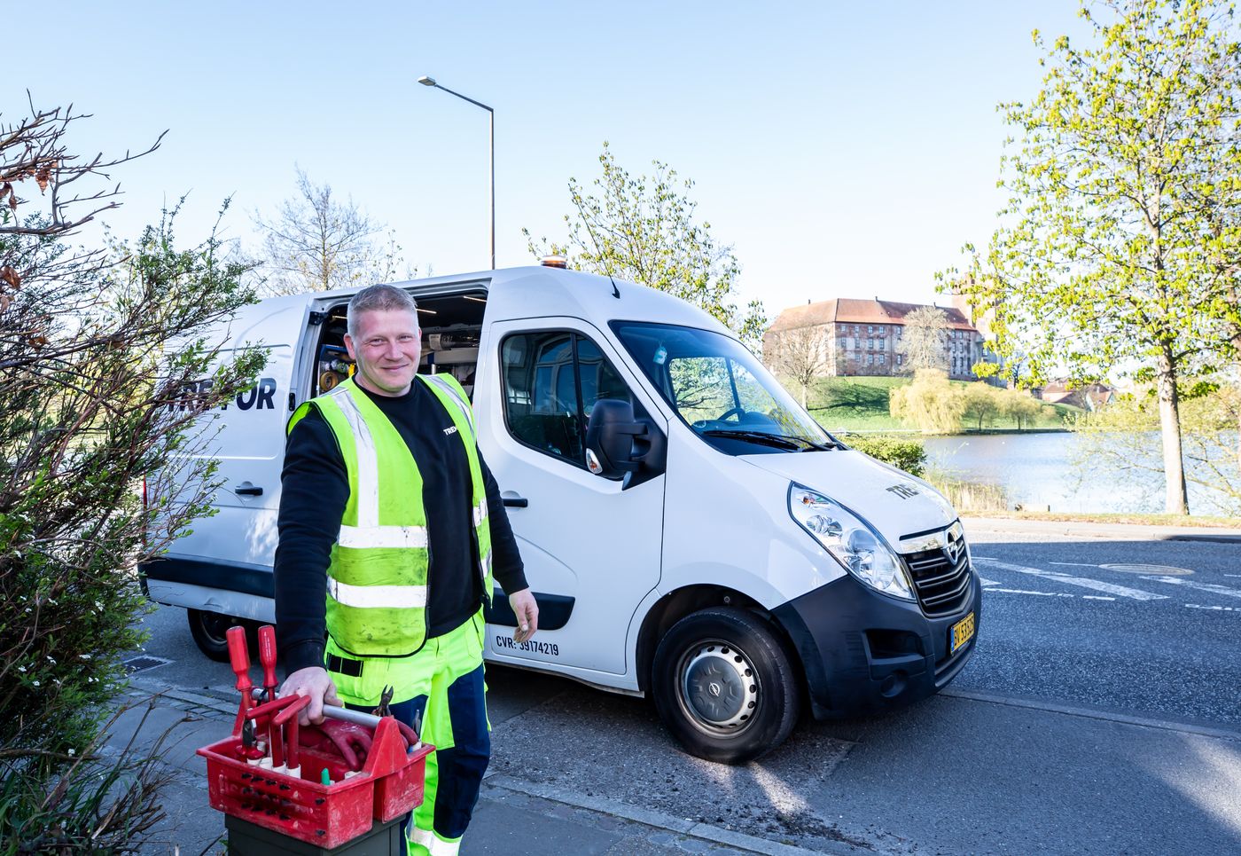 Technicien souriant avec sa camionnette et sa caisse à outils, installateur près de chez soi